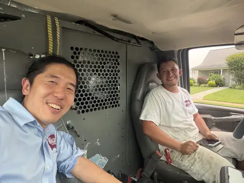 Two crew members sharing a laugh in the work van between jobs