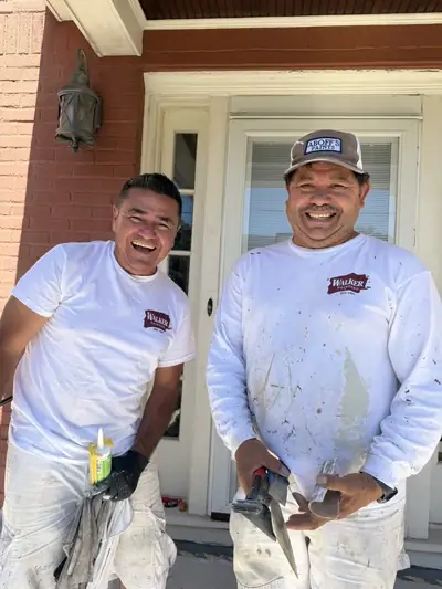 Two Walker Painting crew members sharing a laugh at the front door